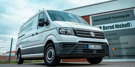 Ein moderner Lieferwagen in Weiß, der für die Firma Bernd Niehoff wirbt, steht vor einem Gebäude mit einem klaren, grauen Himmel im Hintergrund.
