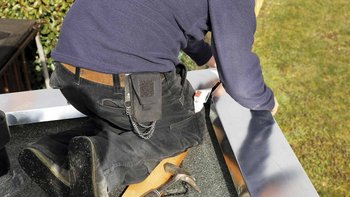 Ein Klempner der Metall auf einem Flachdach bearbeitet